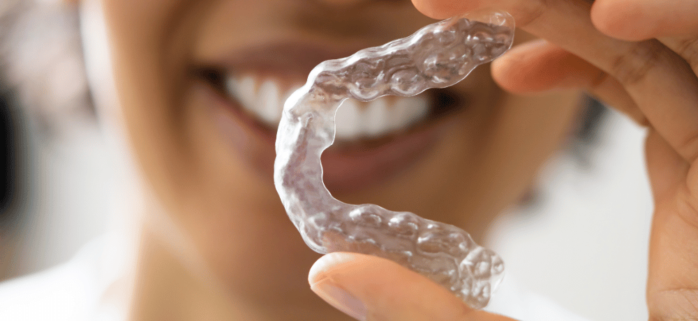 patient håller upp bettskena mot tandgnissling patient håller upp bettskena mot tandgnissling